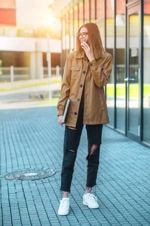 Young girl in glasses talking on smartphone. Woman in the city. Long distance communication. Staying connected.の写真素材