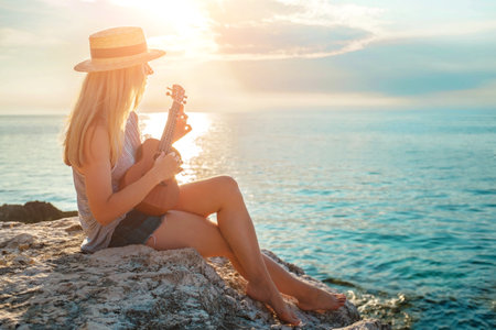 Summer Vacation. Smellingcaucasian women relaxing and playing on ukulele on beach, so happy and luxury in holiday summer, outdoors sunset sky background. Travel and lifestyle Concept.の写真素材