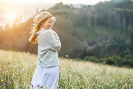 Happy woman enjoying sunset stay on the green grass on the forest peak of mountain. Fresh air, Travel, Summer, Fall, Holidays, Journey, Trip, Lifestyle.の写真素材