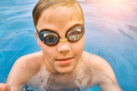 Smiling boy portrait in swimming goggles, Child swim in the pool, sunbathes, swimming in hot summer day. Relax, Travel, Holidays, Freedom concept. 4K slow motionの写真素材
