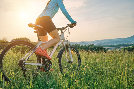 Cyclist Woman riding bike in helmets go in sports outdoors on sunny day a mountain in the forest. Silhouette female at sunset. Fresh air. Health care, authenticity, sense of balance and calmness.の写真素材