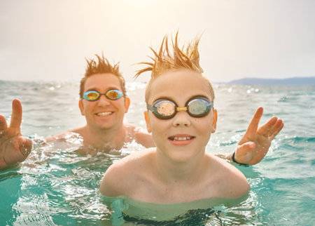 Happy family in swimming goggles, father and son bonding, play, swim in the sea looking at view enjoying summer vacation. Togetherness Friendly conceptの写真素材