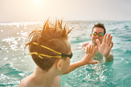 Happy family in swimming goggles, father and son bonding, play, swim in the sea looking at view enjoying summer vacation. Togetherness Friendly conceptの写真素材