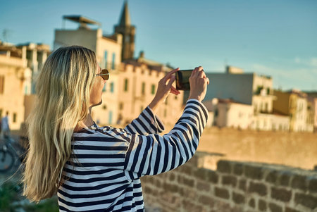 Woman traveler tourist using smartphone, taking photo of sea view at sunset in summer day. Enjoying European, Famous popular touristic place in world.の写真素材