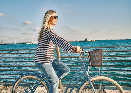 Carefree woman with bike riding on beach having fun, on the seaside promenade on a summer day. Summer Vacation. Travel and lifestyle Concept.の写真素材