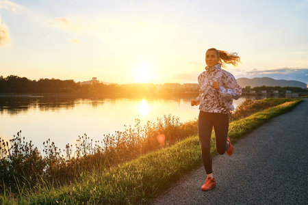 Woman runs in the park on autumn morning. Healthy lifestyle concept, people go in sports outdoors. Silhouette family at sunset. Fresh air. Health care, authenticity, sense of balance and calmness.の写真素材