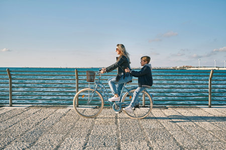 Happy family, Carefree mother and son with bike riding on beach having fun, on the seaside promenade on a summer day, enjoying vacation. Togetherness Friendly conceptの写真素材