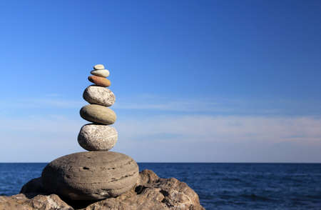 Zen stones. Zen stone pyramid illuminated by the rays of the evening sun against the background of the sea.の写真素材