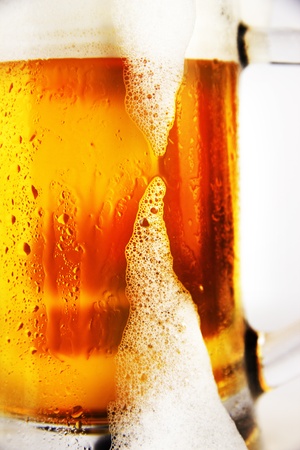 cold glass of beer with foam on a white backgroundの写真素材
