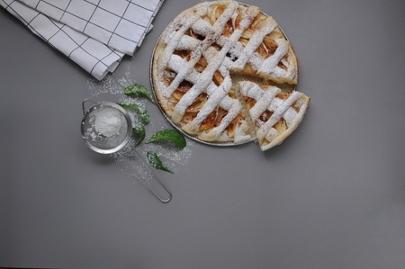 Apple pie with white towel on gray background. Dessert. Homemade cake with sieve. Autumn flatlay....