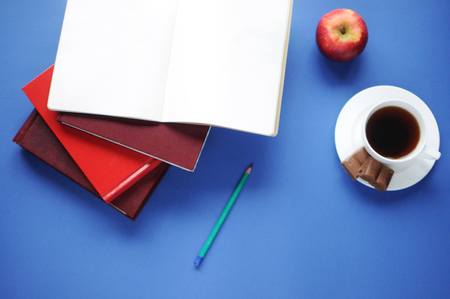 Study stuff. Education background. Stationery. Aspects of education. Food for brain. Pencil, opened notebook, books, an apple, coffee and chocolate on the table.の写真素材