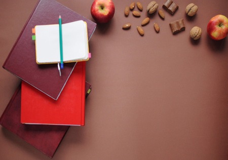 Study stuff. Education background. Stationery. Aspects of education. Food for brain. Pencil, opened notebook, books, apples, almonds, nuts and chocolate on the table.の写真素材