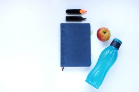 Study stuff. Education background. Stationery. Aspects of education. Markers, apple, blue bottle and notebook on the table.の写真素材