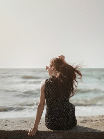 Girl sitting on the beach and looking at the seaの写真素材