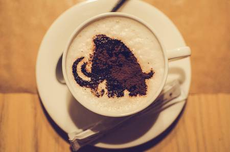 Cup of coffee with foam of mammoth image in cafe.の写真素材