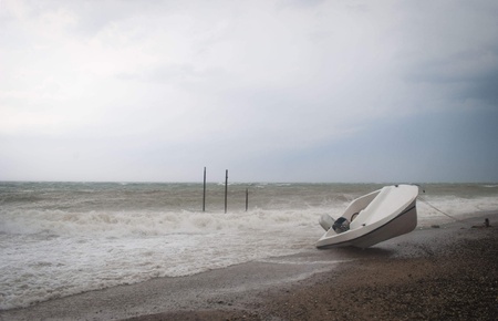 Storm on the sea with overturn boat on the beach.の写真素材