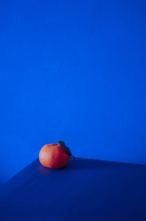 Tangerine on the corner of the table on classic blue background color of the year 2020の写真素材
