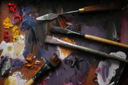 Paintbrushes and paints while drawing on oil paint backgroundの写真素材
