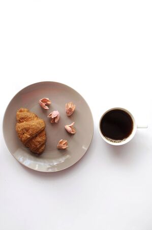 Breakfast with croissant on the plate with coffee and decorated flowers top viewの写真素材