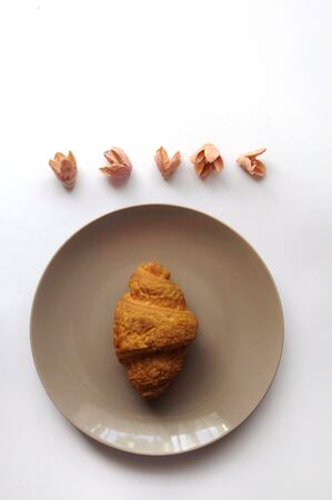 Croissant on the plate with decorated flowers top view