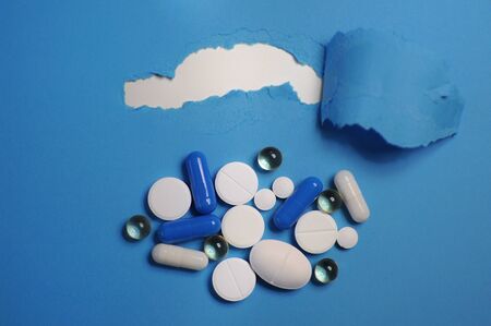 Diferent colorful pills on blue table. Medicine against COVID-19 and diseases
