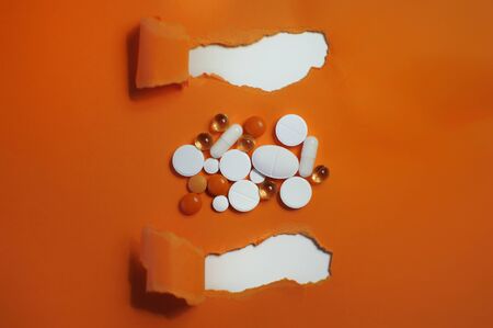 Many colorful pills with title on orange background. Medicine against COVID-19の写真素材
