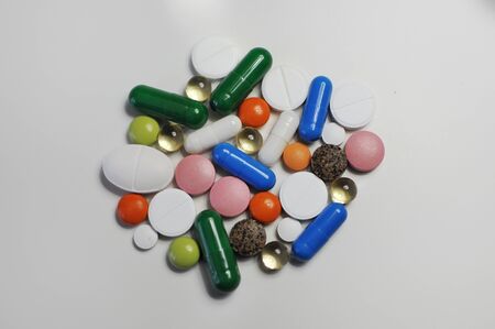 Many different pills on white table. A lot of colorful different pills including anti-viral drugs....