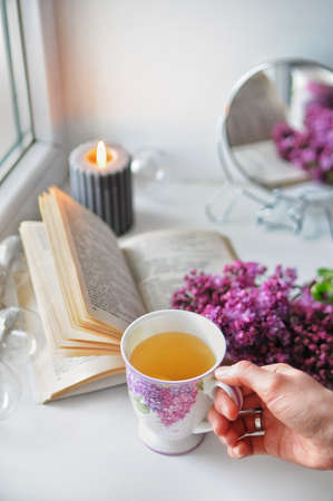 Opened book with a lilac bush. Cozy romantic home atmosphere with a candle.