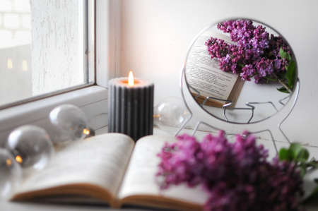 Beautiful cozy romantic corner at home with opened book and with a lilac bush.
