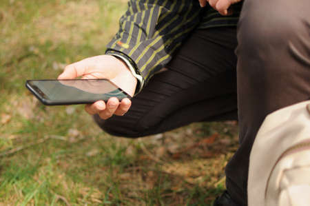 Man traveller is looking for a way using gps navigator on phone in forest aloneの写真素材