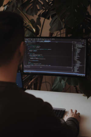 Man freelancer is working at home. Programmer is coding. Programming screen.の写真素材