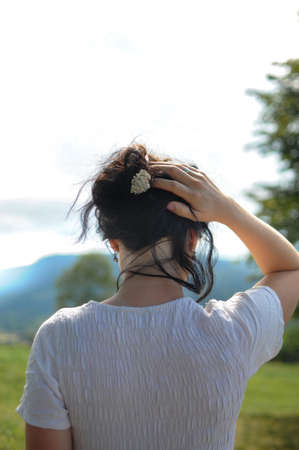 Natural style in the mountains. Woman is holding her hair with the little flower