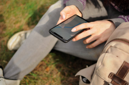 Woman tourist is looking for path through gps navigator on phone in forest aloneの写真素材
