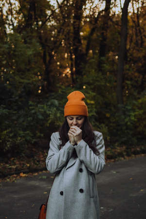 Young woman breathing into her hands in woolen coat outsideの写真素材