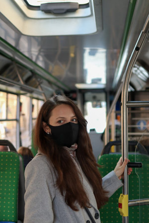 Young European woman passenger wearing a face mask and looking at camera in busの写真素材