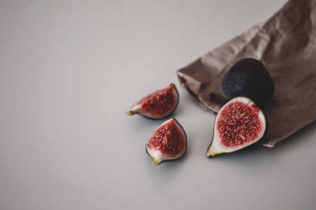Fresh fruit harvest of ripe figs whole and halved, on the brown craft paper