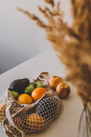 A variety of fruits in an eco-aware handbag are lying on the table. Healthy flat lay with copy...