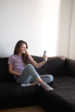 A happy woman is talking to someone using smartphoneの写真素材