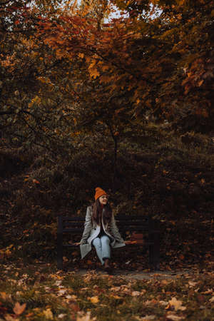 Young woman sitting on bench alone in fall season