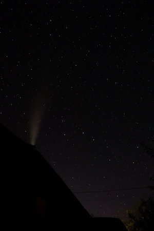Starry sky with the milky way above the silhouette of chimney house in the village