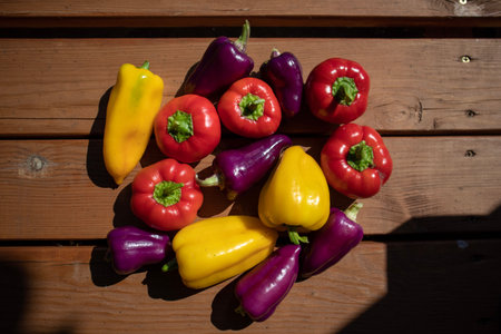 Group of colorful peppers on wooden background. Red, yellow, purple, and red hot chilly pepper