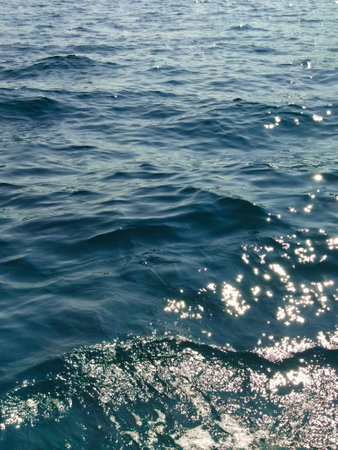 Water surface with waves and sunny rays on a summer day