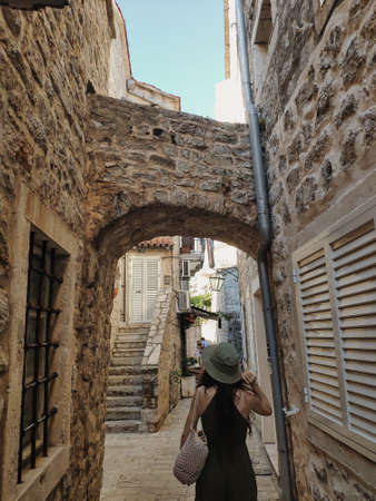 Woman walking in tiny street with stone buildings in old town Budva, Montenegroの写真素材