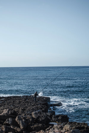 Man is fishing in the sea from the cliff in Cyprus