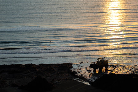 Beautiful sunrise with a tractor silhouette working near the sea In Larnaca, Cyprus.