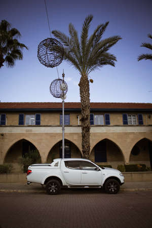 Modern stylish car in front of the building with arches, palm trees in sunny day