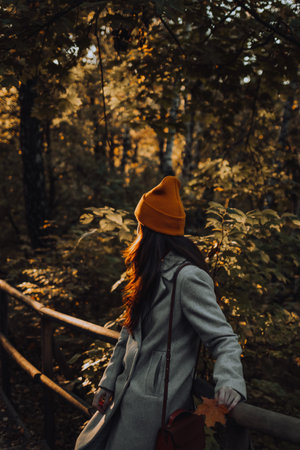Young girl is standing back outside in colorful orange hat alone on the streetの写真素材