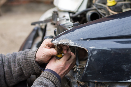 Repair service worker fix damaged car after crash on the road. Working with pliers to align metal body.の写真素材