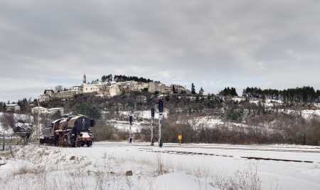 Old steam locomotive abandoned in a snowy landscape, a medieval village in the backgroundの写真素材