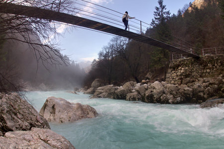 Person crossing a bridge over the river Soca, italian Isonzo, in Slovenia  